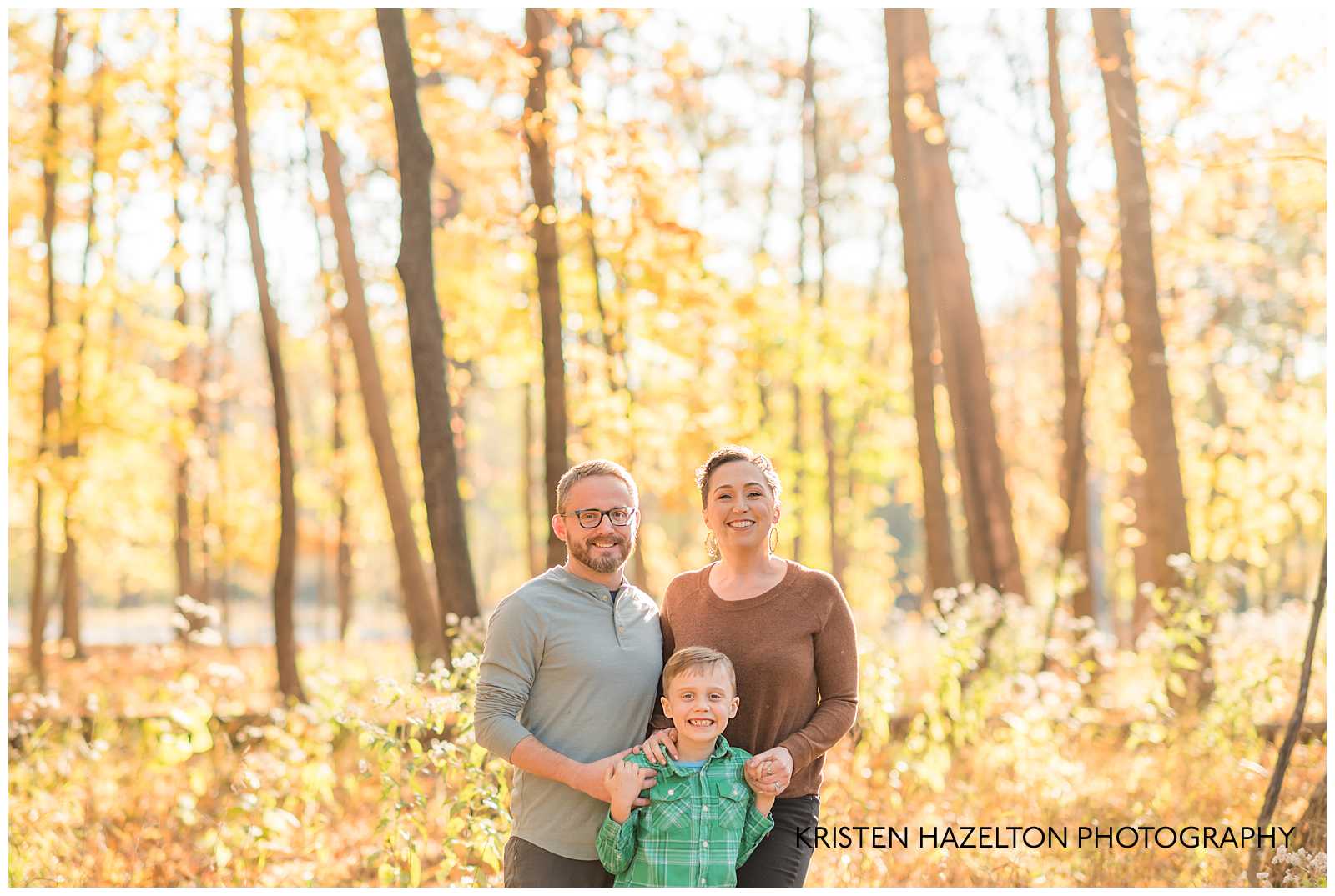 Family of three in fall woods with yellow leaves 