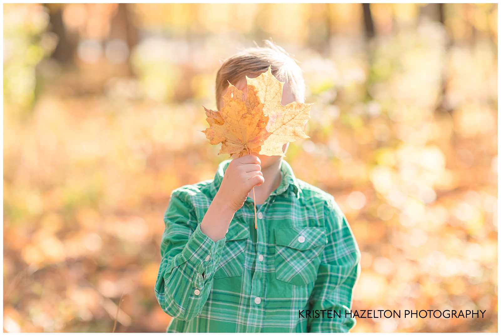 Young boy hiding behind a leaf