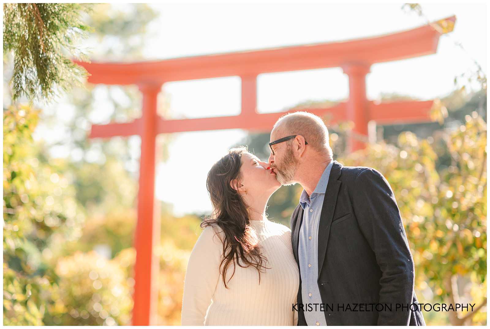 Man and woman kissing under a Shinto Torii gate