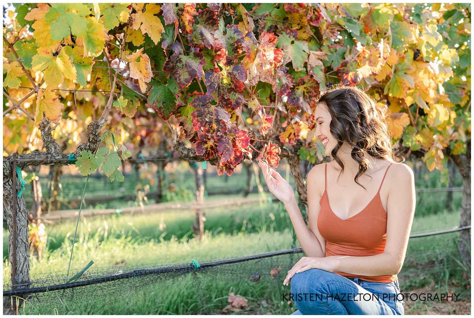 Girl looking at a grape leaf and smiling by Livermore Senior Photographer Kristen Hazelton