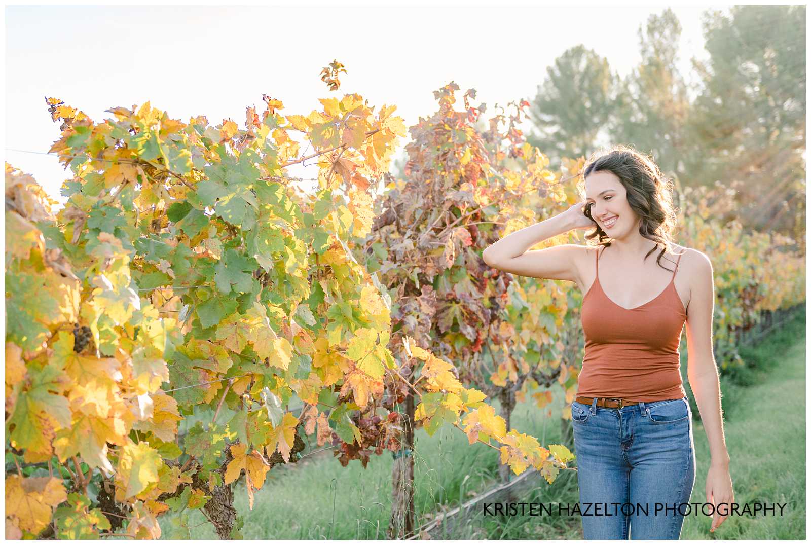 Girl in orange shirt walking next to grape vines by Livermore Senior Photographer Kristen Hazelton