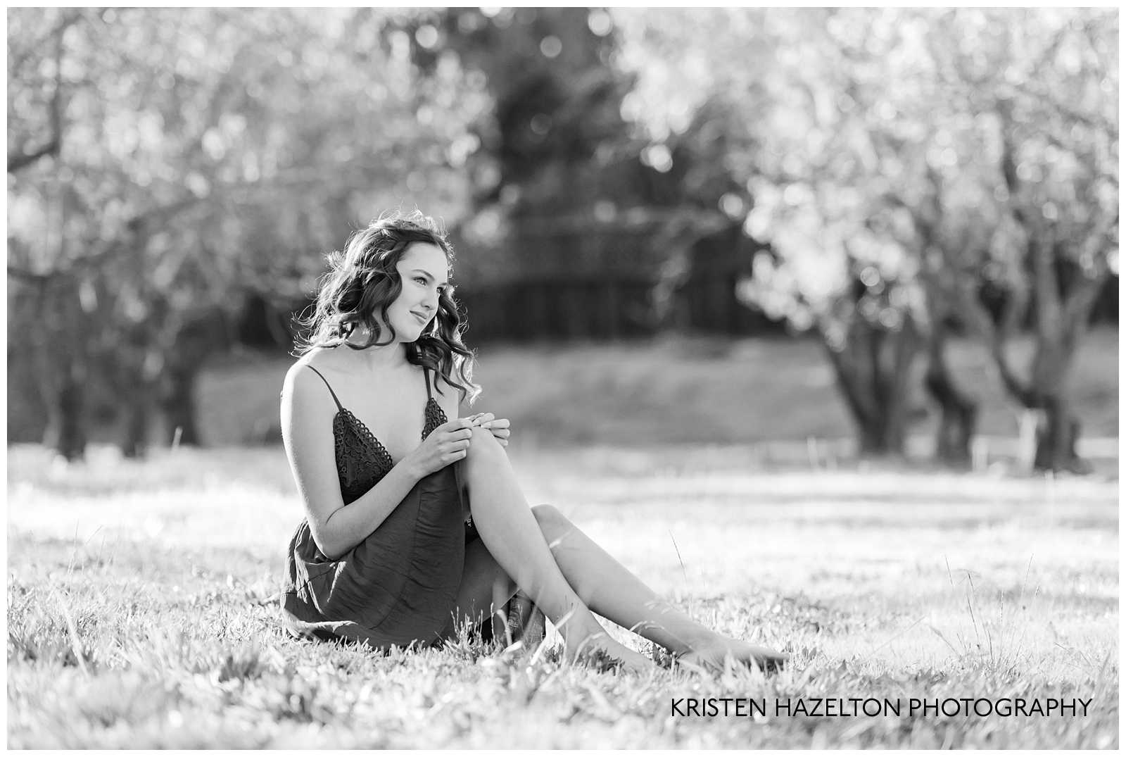 Black and white photo of a girl sitting in an orchard at Ravenswood in Livermore, CA