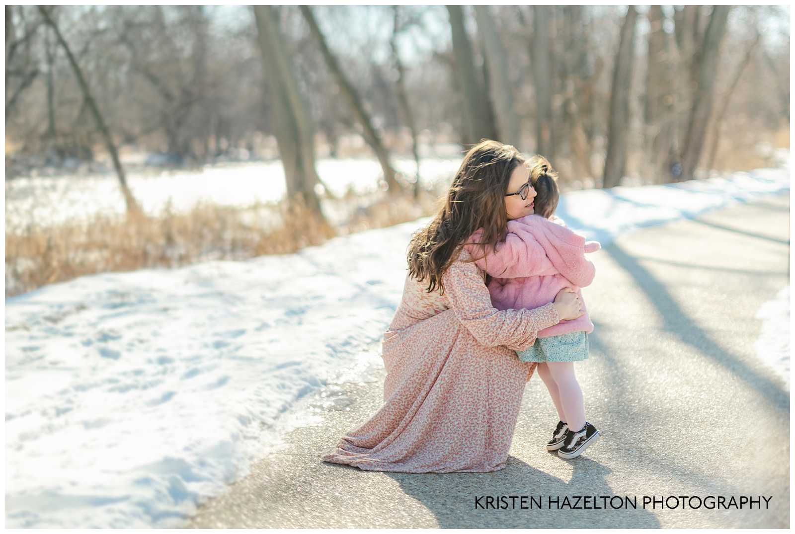 Mom in pink dress hugging her toddler daughter at a Winter Family Photoshoot