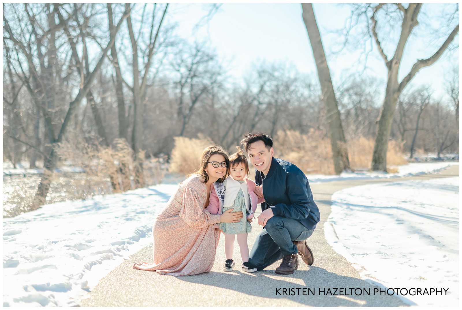 Mom and Dad crouched down next to toddler daughter at a Winter Family Photoshoot