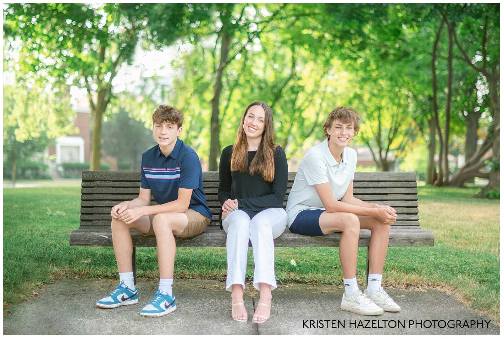 Three teenage siblings seated on a park bench at their family photos with teens by Chicago photographer Kristen Hazelton.