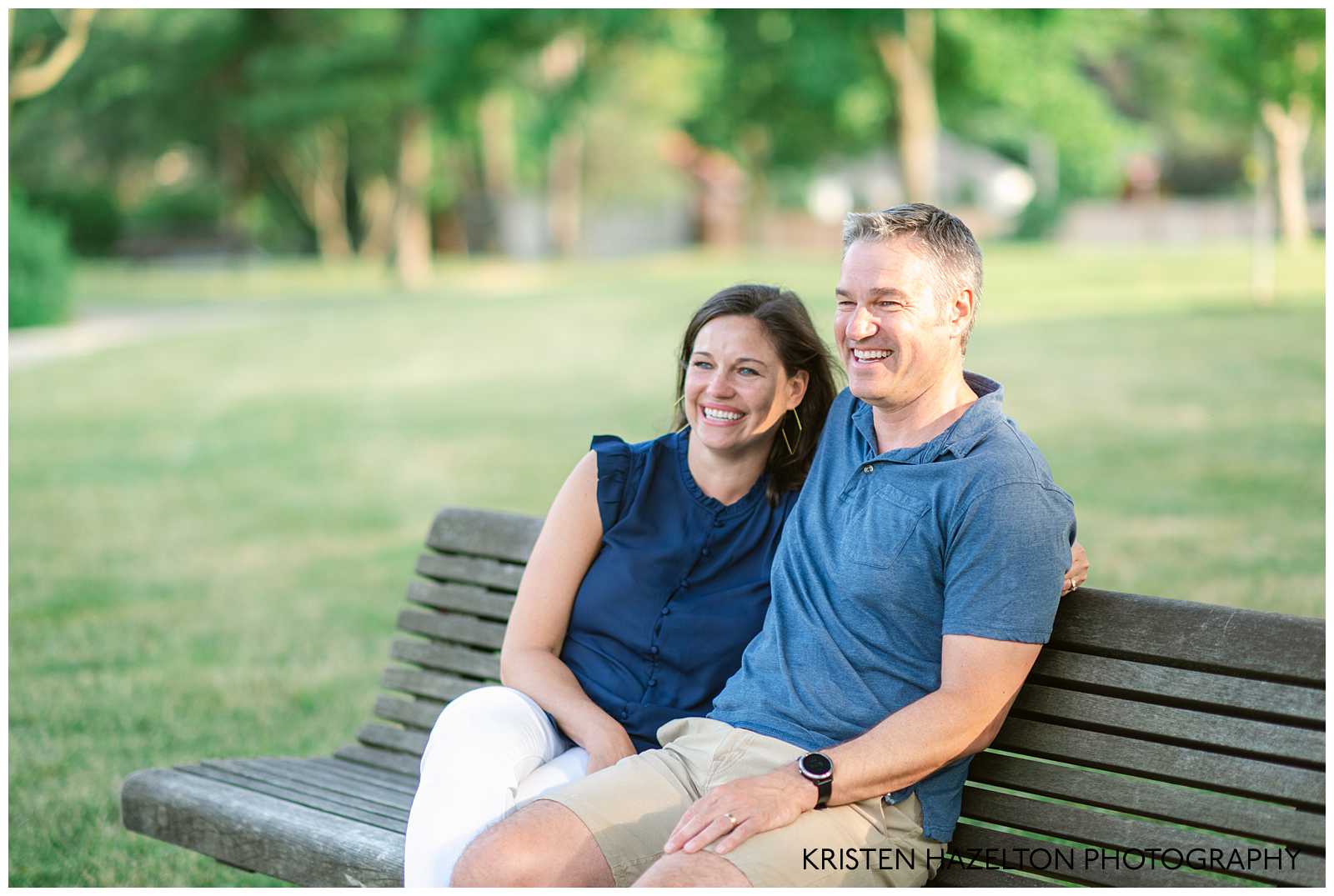 Man and woman wearing blue shirts sitting on a park bench.