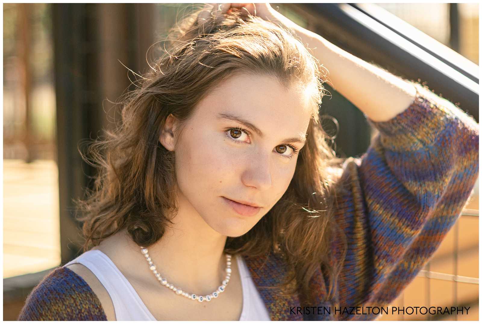 Closeup portrait of a high school senior girl wearing a brown and blue striped cardigan
