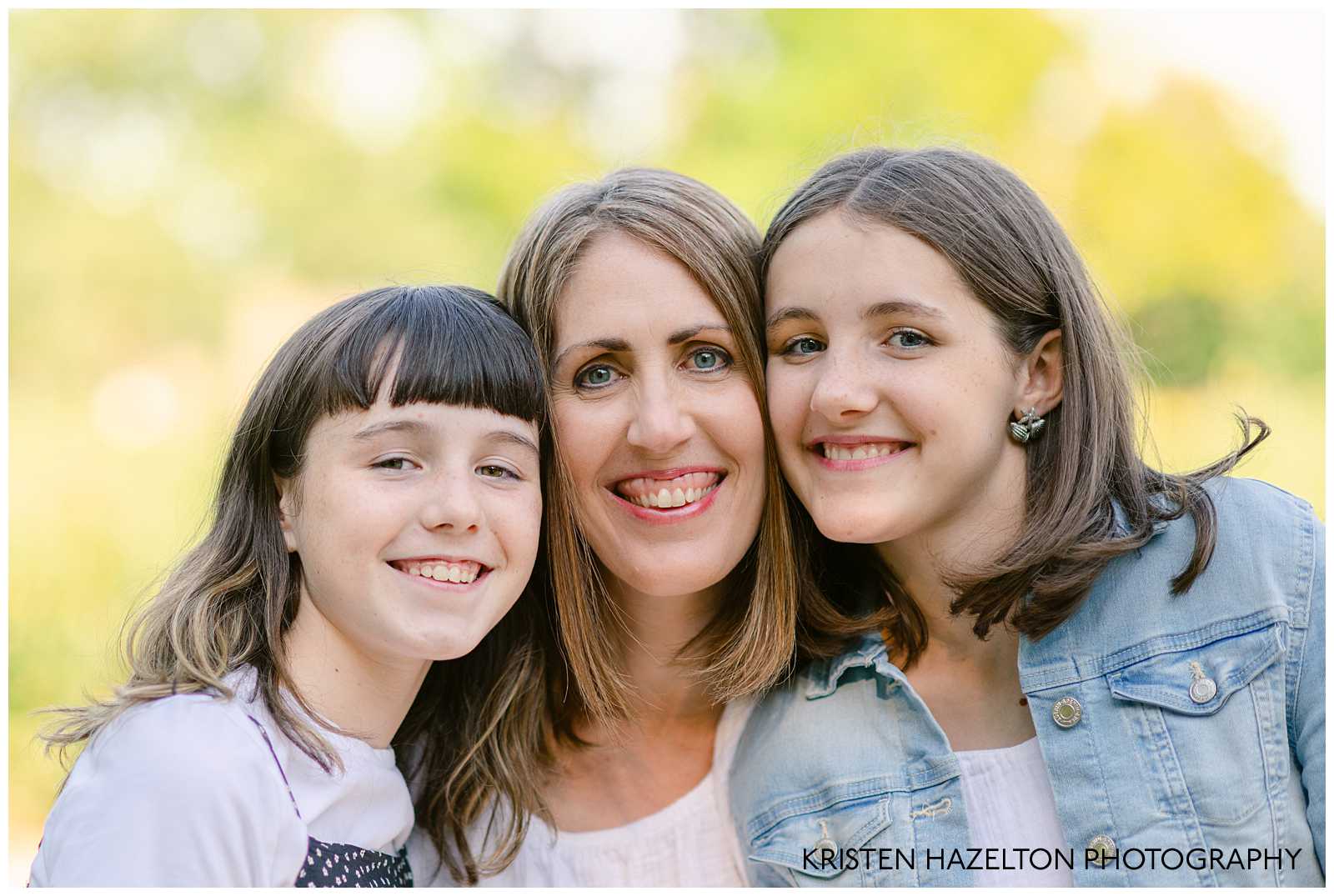 Closeup family photo of a mom and her two tween daughters cheek to cheek. 