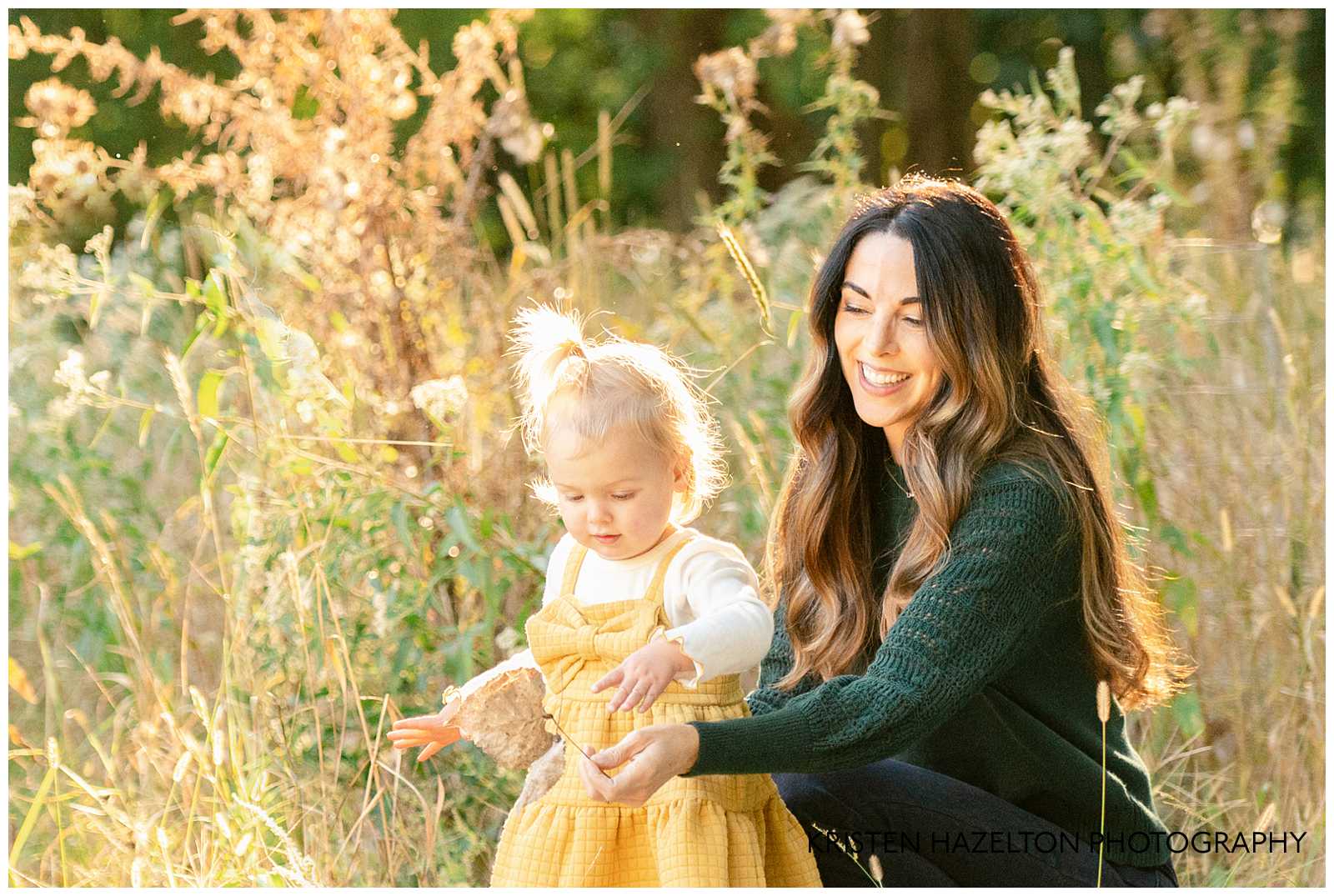 Mom handing her toddler daughter a leaf at their fall family photoshoot