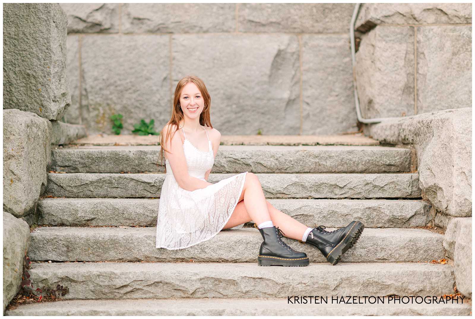 High school senior photos at Lincoln Park zoo in Chicago, IL; a girl in a white dress and Doc Marten boots seated on stone steps