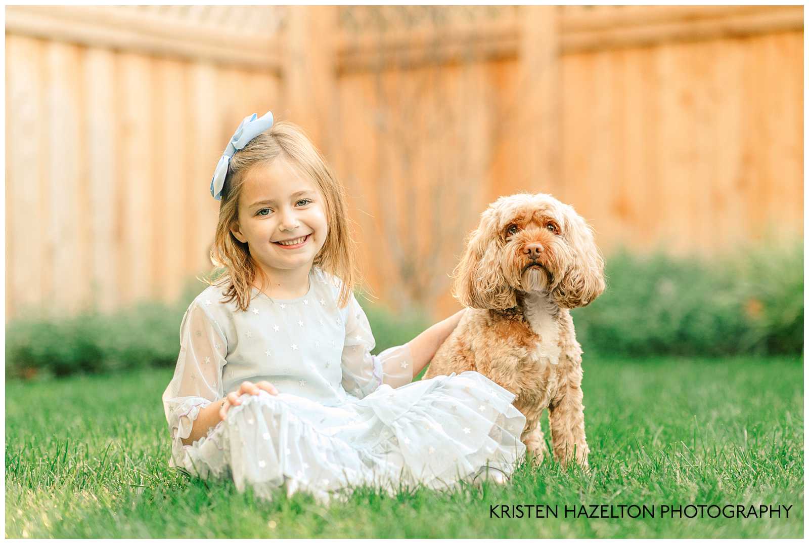 Young girl sitting on grass with her dog.
