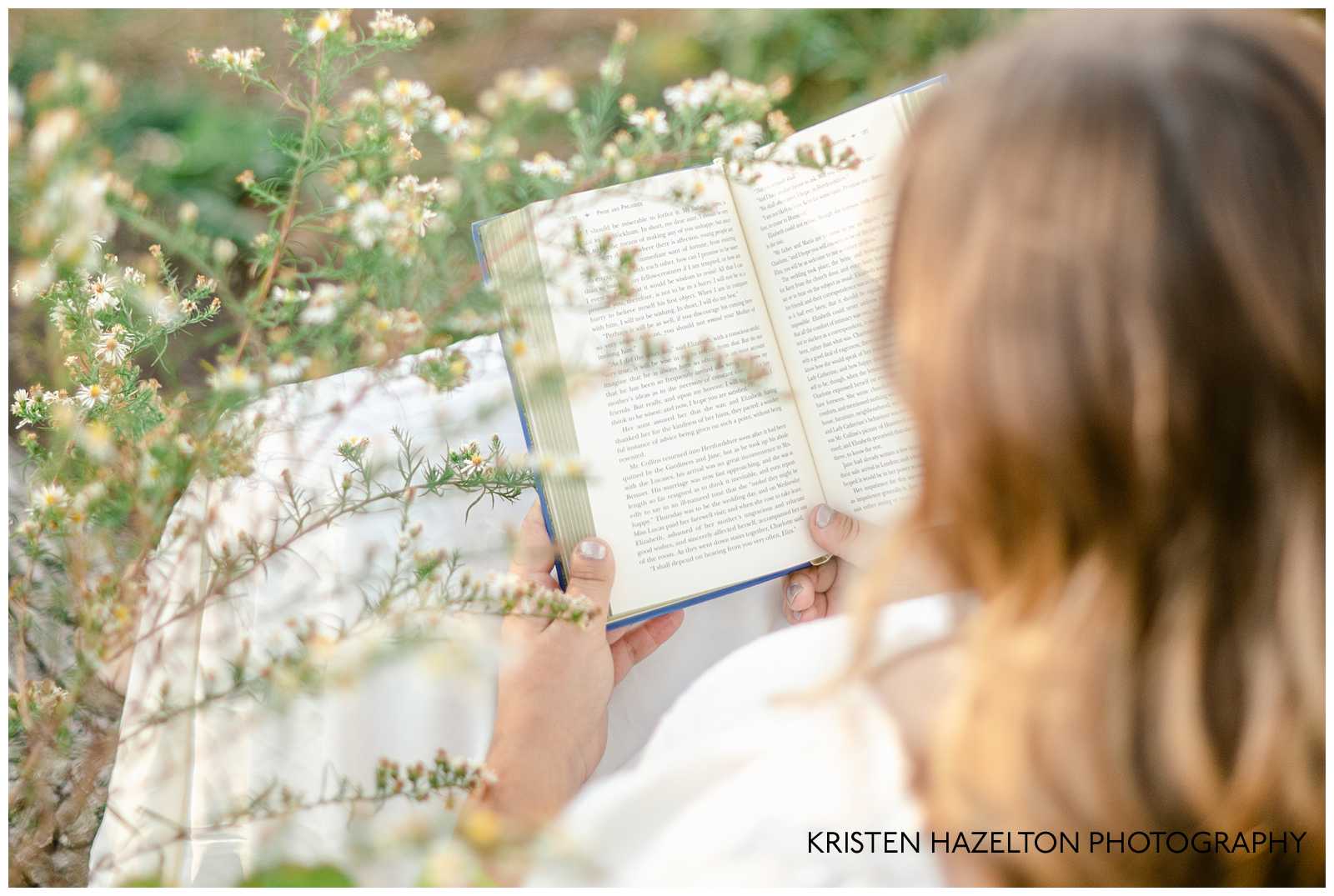 Books aesthetic senior photoshoot; a girl reading in a meadow next to white wildflowers