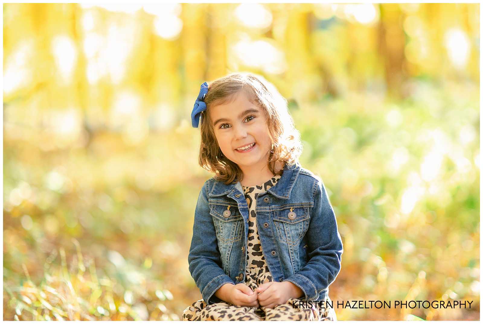 Little girl wearing a blue denim jacket and leopard print dress in the woods in River Forest, IL