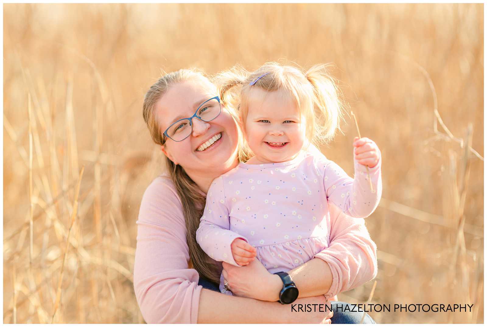 Mom hugging her toddler daughter in a field of yellow grass