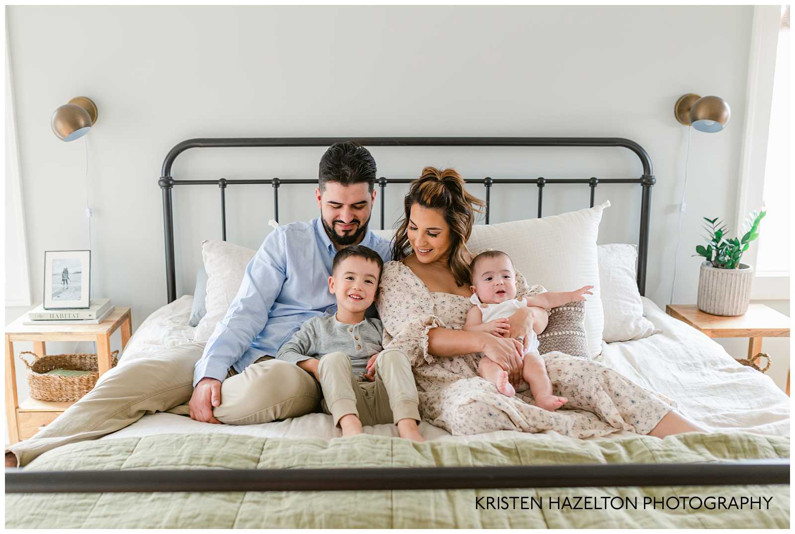 Family of four on a bed for an indoor winter photoshoot. Winter photoshoot ideas by Kristen Hazelton