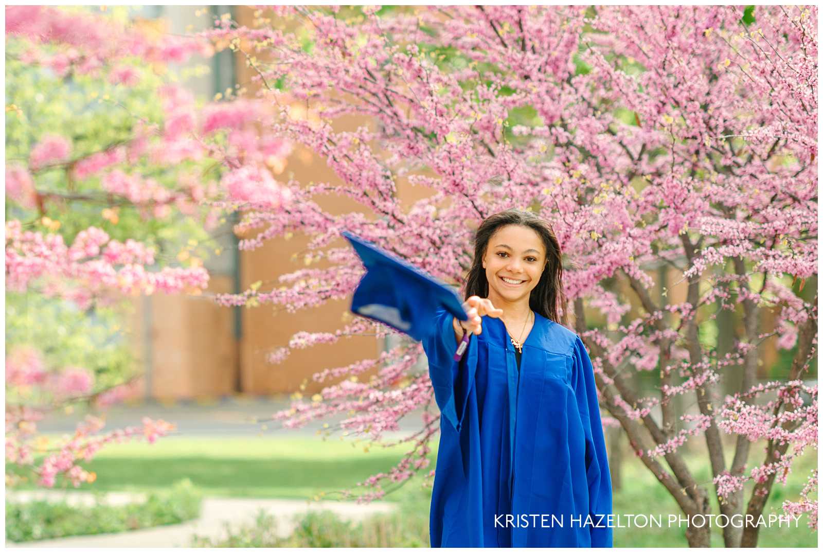 High school graduate in a blue robe throwing her cap towards you