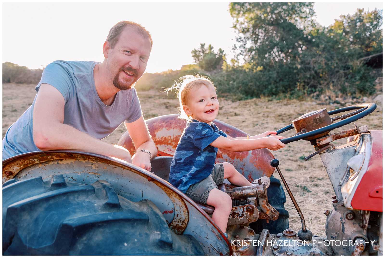 Toddler boy driving an old tractor with Dad