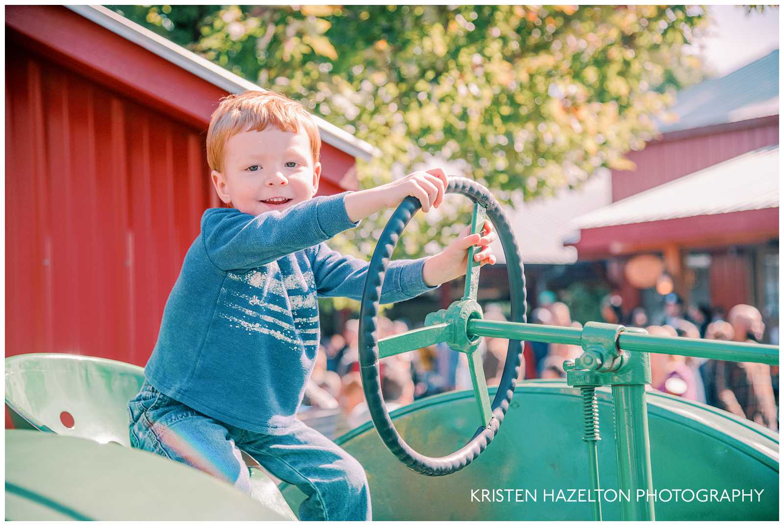 Little boy driving a tractor at a pumpkin patch