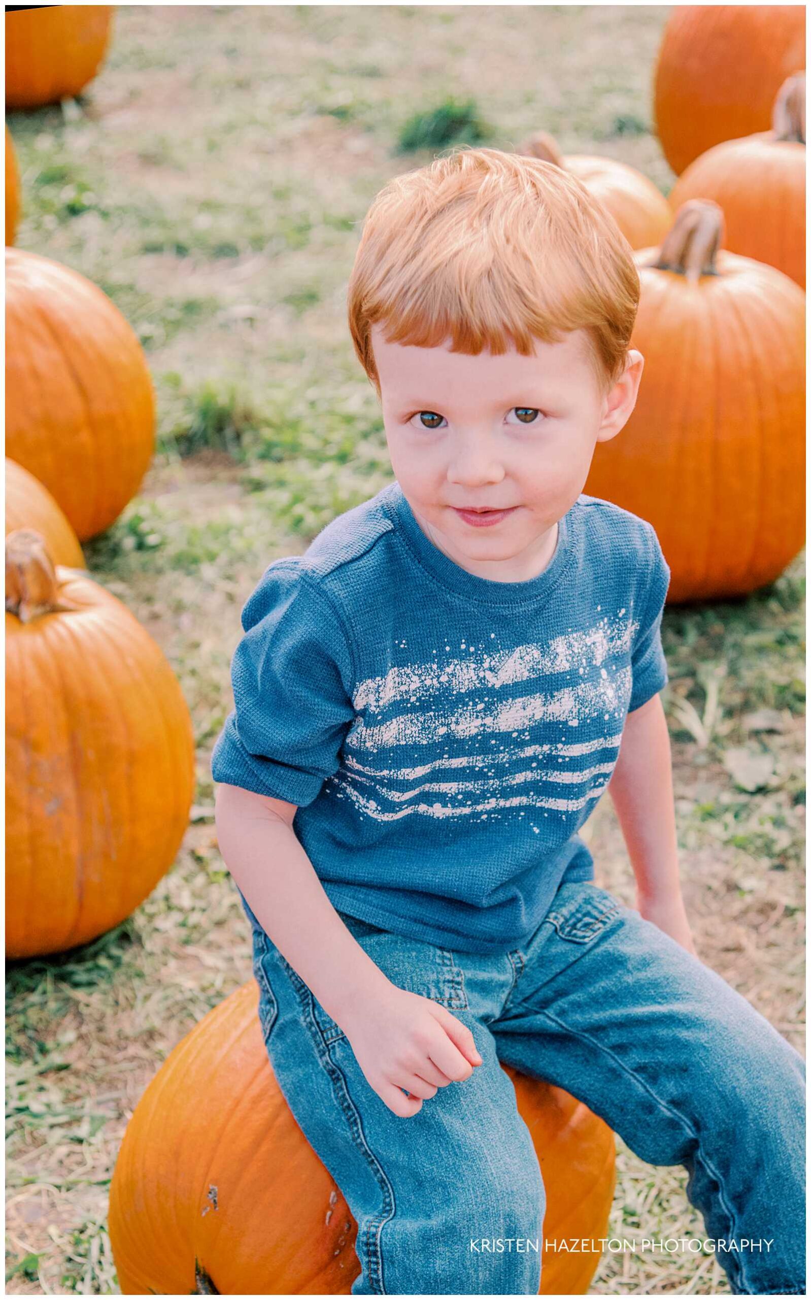 Little boy sitting on a pumpkin at one of the best pumpkin patches in Chicago