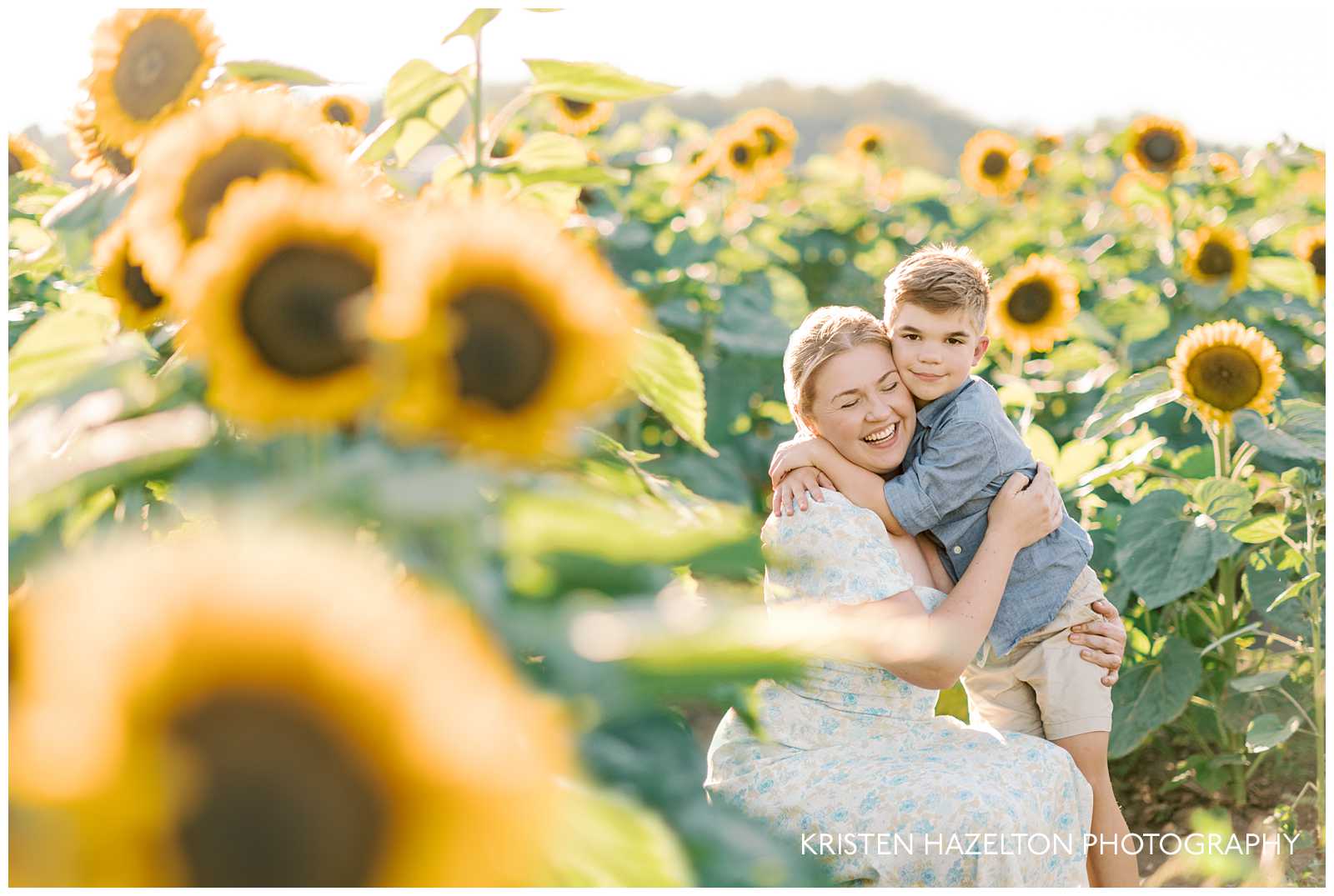 mother wearing a white dress with small blue flowers and son wearing a blue button up shirt and khaki shorts for their sunflower field outfits