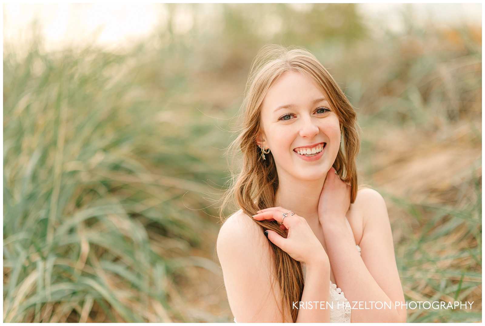 High school senior girl sitting in grasses and sand dunes at one of Chicago's best beaches