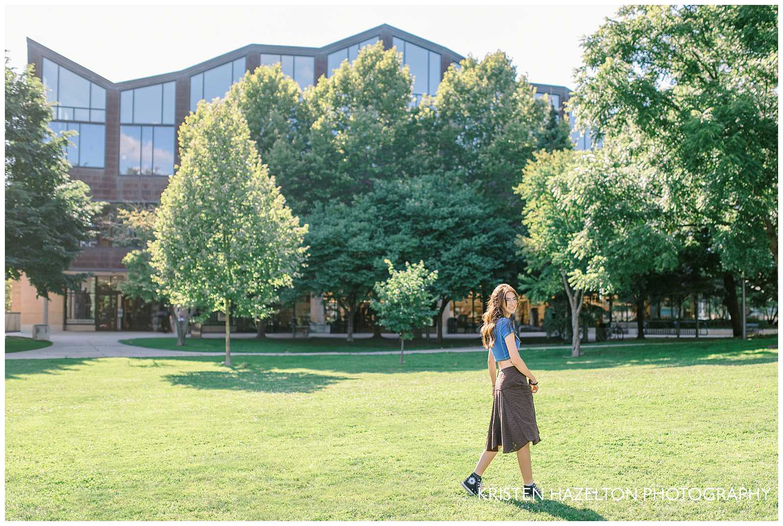 Library photoshoot ideas: a girl wearing a blue shirt and brown skirt walking in front of the library in Oak Park, IL