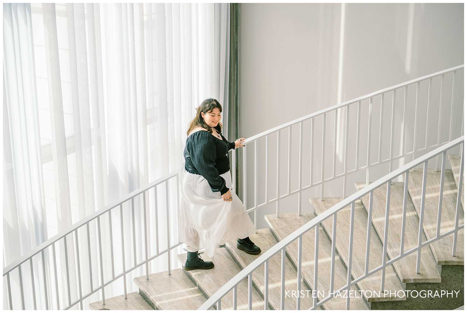 Girl in black top wearing a white skirt walking up a staircase for her museum photos at the Art Institute of Chicago