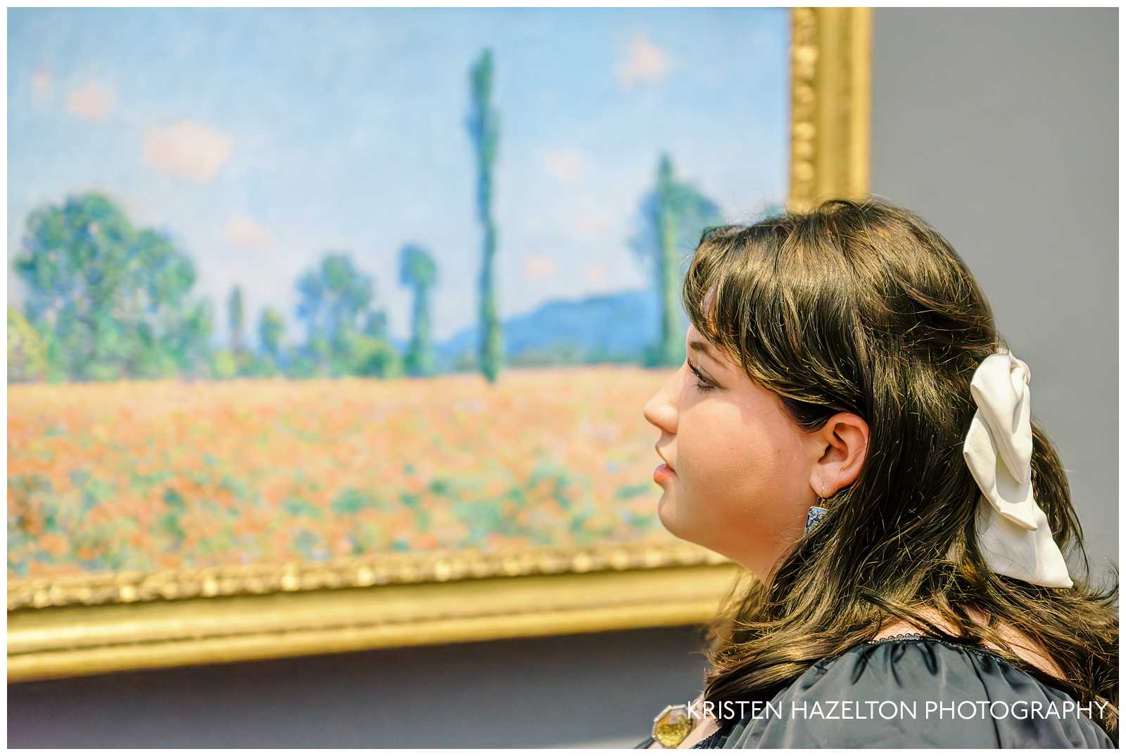 Girl with white ribbon in her hair looking at a painting