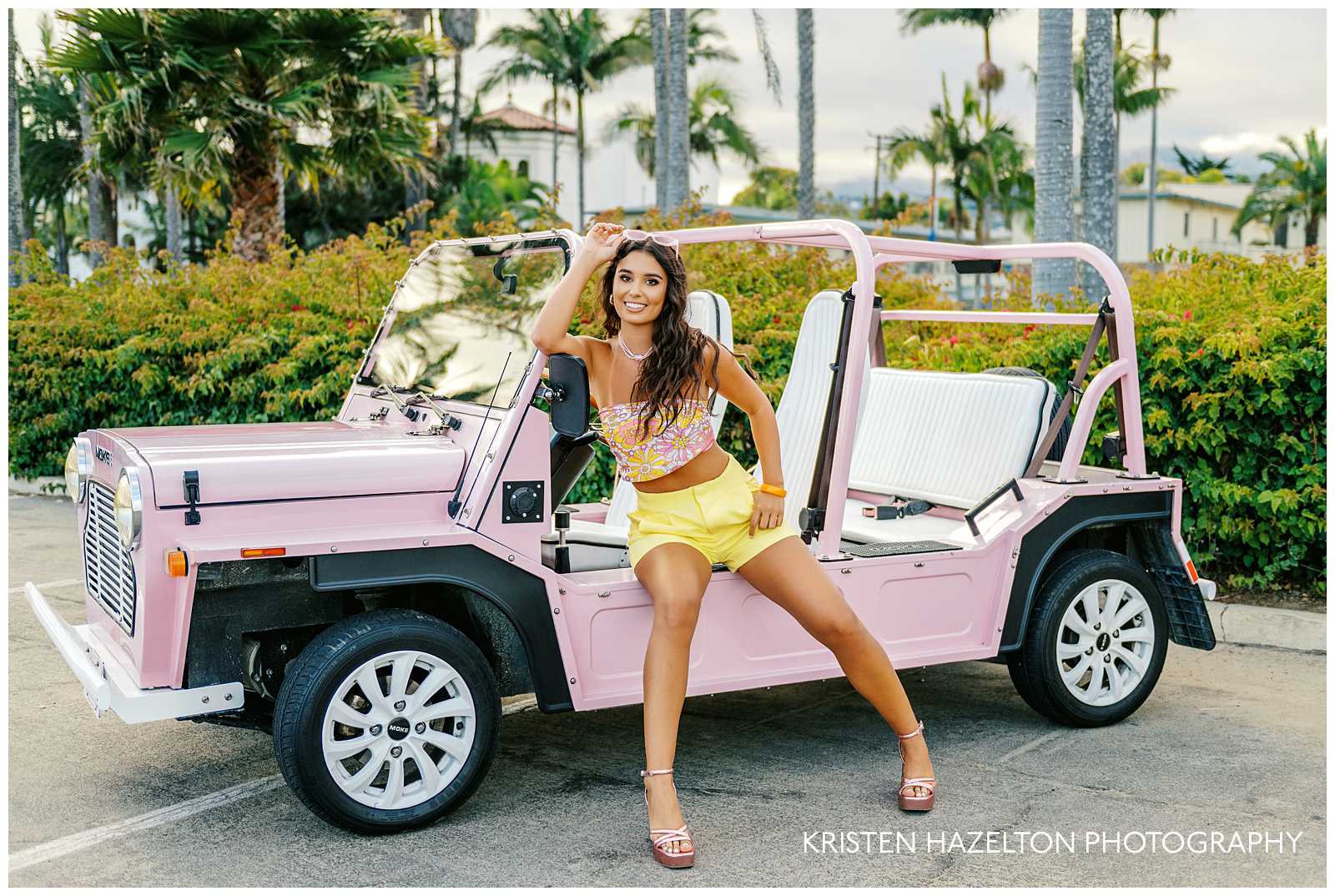 Girl sitting on the side of a pink MOKE electric vehicle