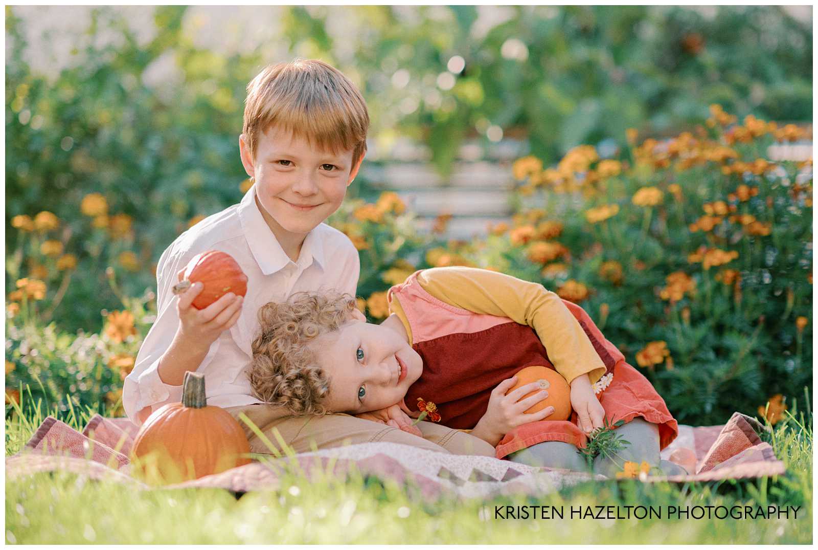 Little girl and boy sitting on a quilt for backyard for fall photos with pumpkins acquired from a pumpkin patch by Chicago.
