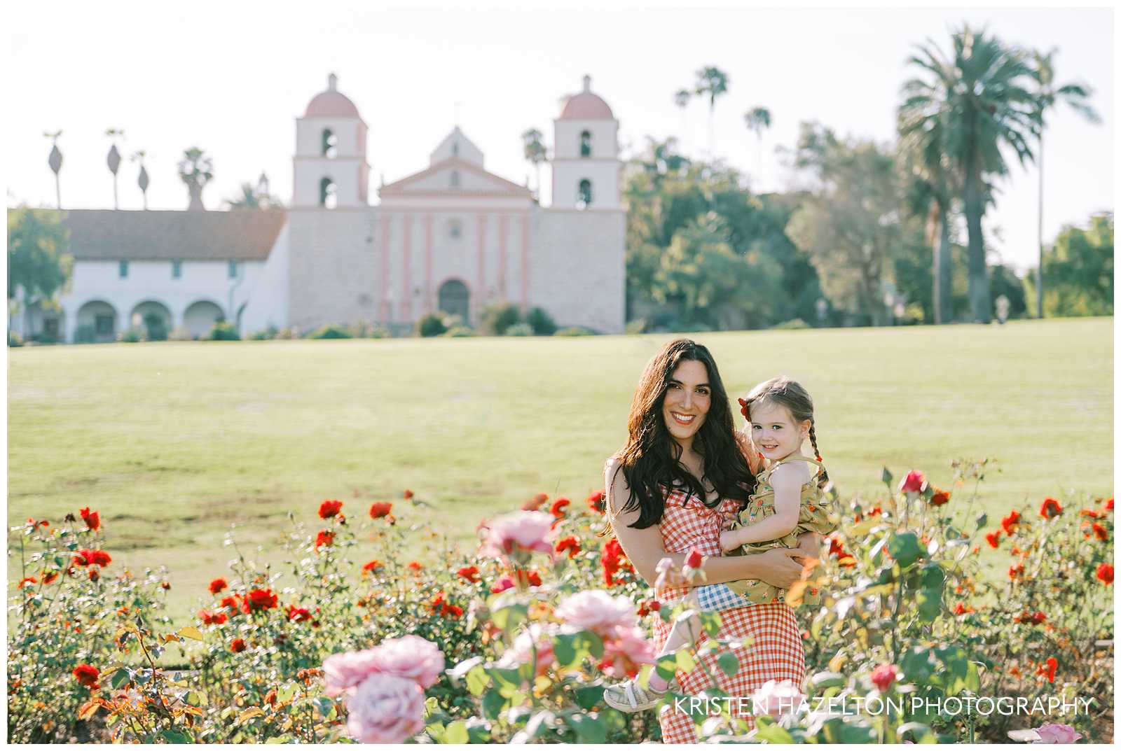 Portrait of mom holding her toddler daughter in front of the Santa Barbara mission for their photos with Santa Barbara family photographer Kristen Hazelton