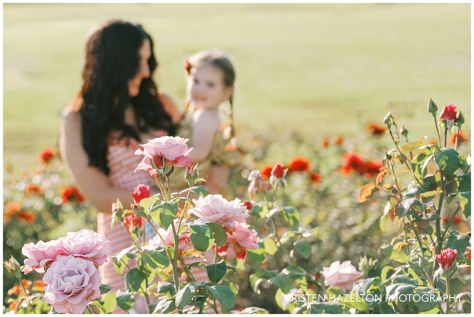 Mom holding her daughter while walking through a rose garden for their portraits with Santa Barbara family photographer Kristen Hazelton