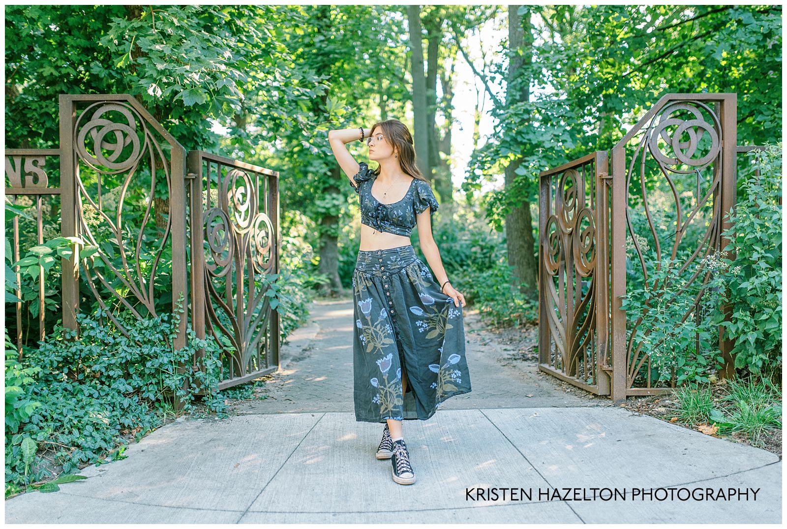 Girl in black floral festival outfit standing at the gates to Austin Gardens in Oak Park, IL