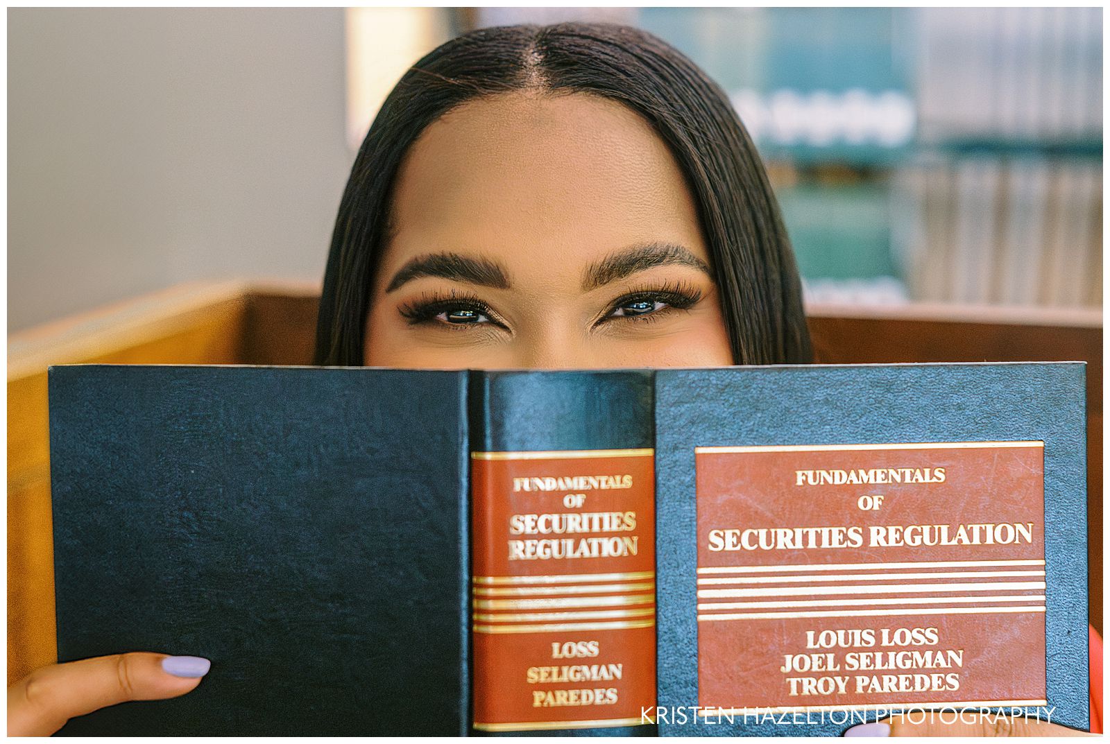 Woman looking up over the top of a book about securities regulation for her law school graduation photos