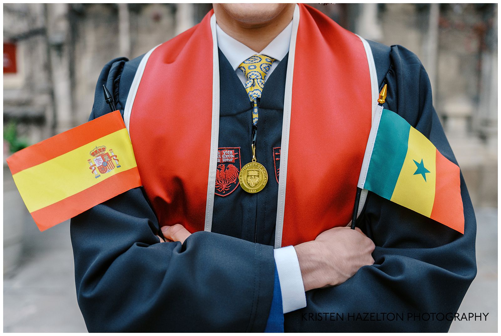 University graduate holding small flags for Spain and Senegal