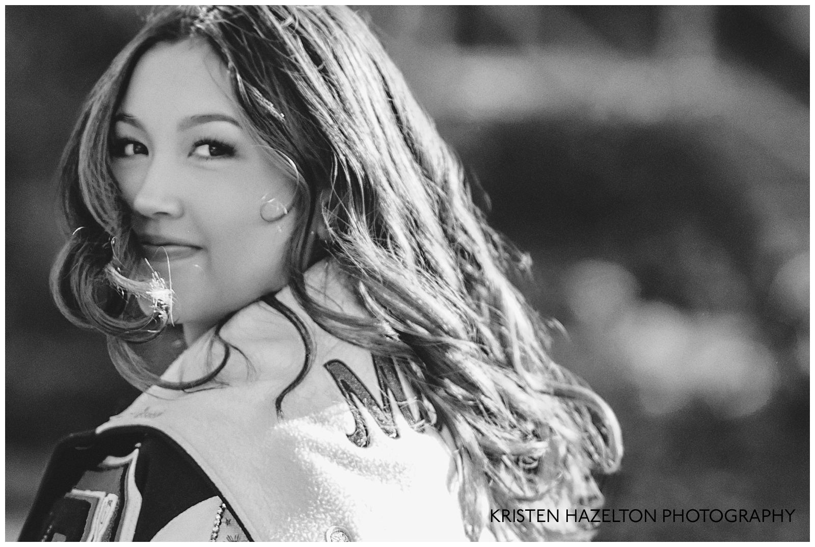 Black and white photo of a high school senior girl wearing a varsity jacket