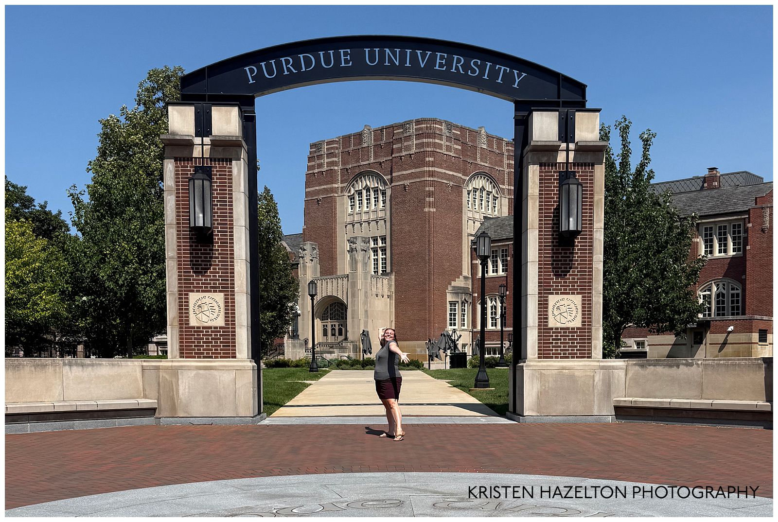 Purdue graduation photos: A woman stands in front of the Purdue University arch.
