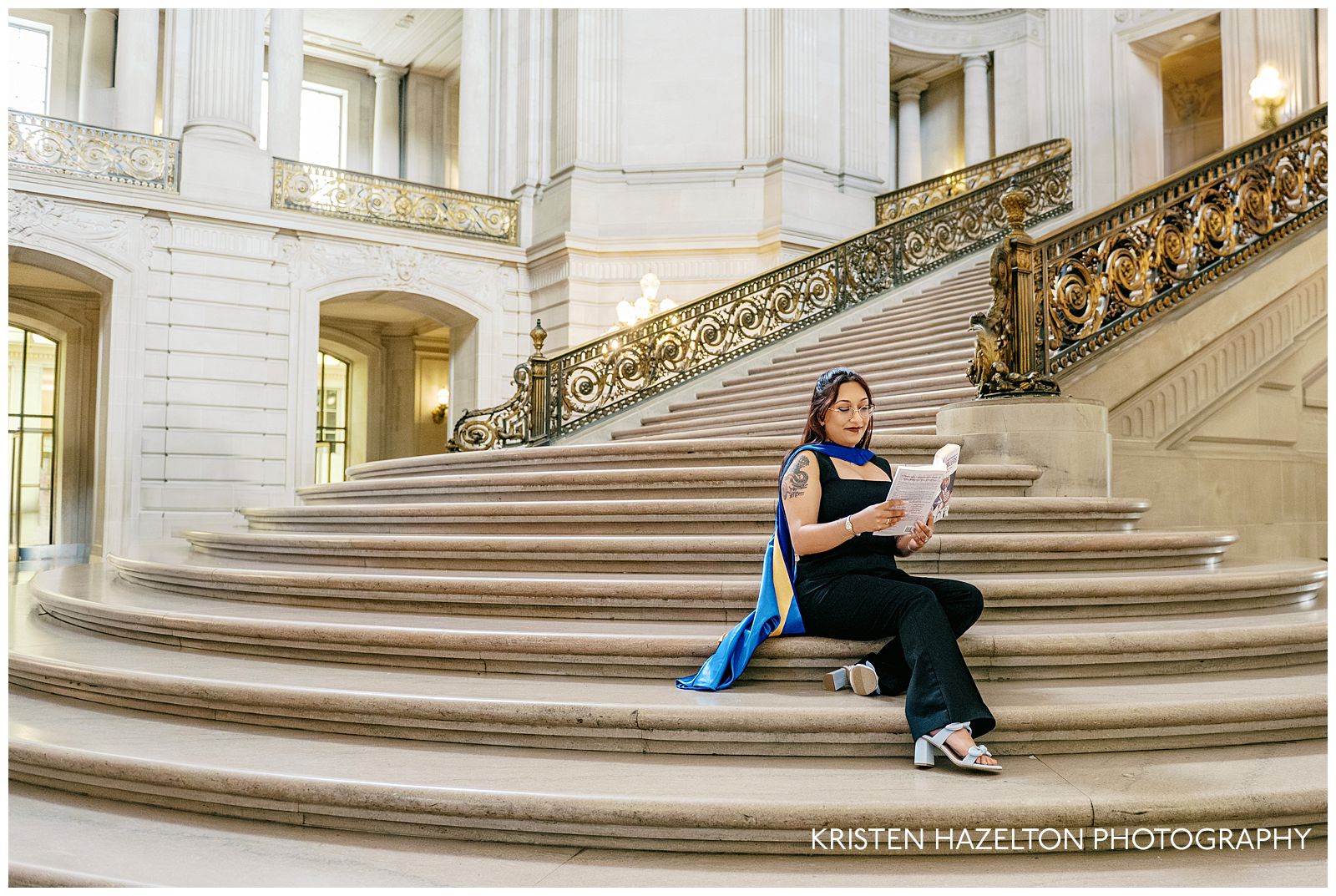 PhD grad student wearing blue regalia taking grad portraits at her San Francisco City Hall photoshoot