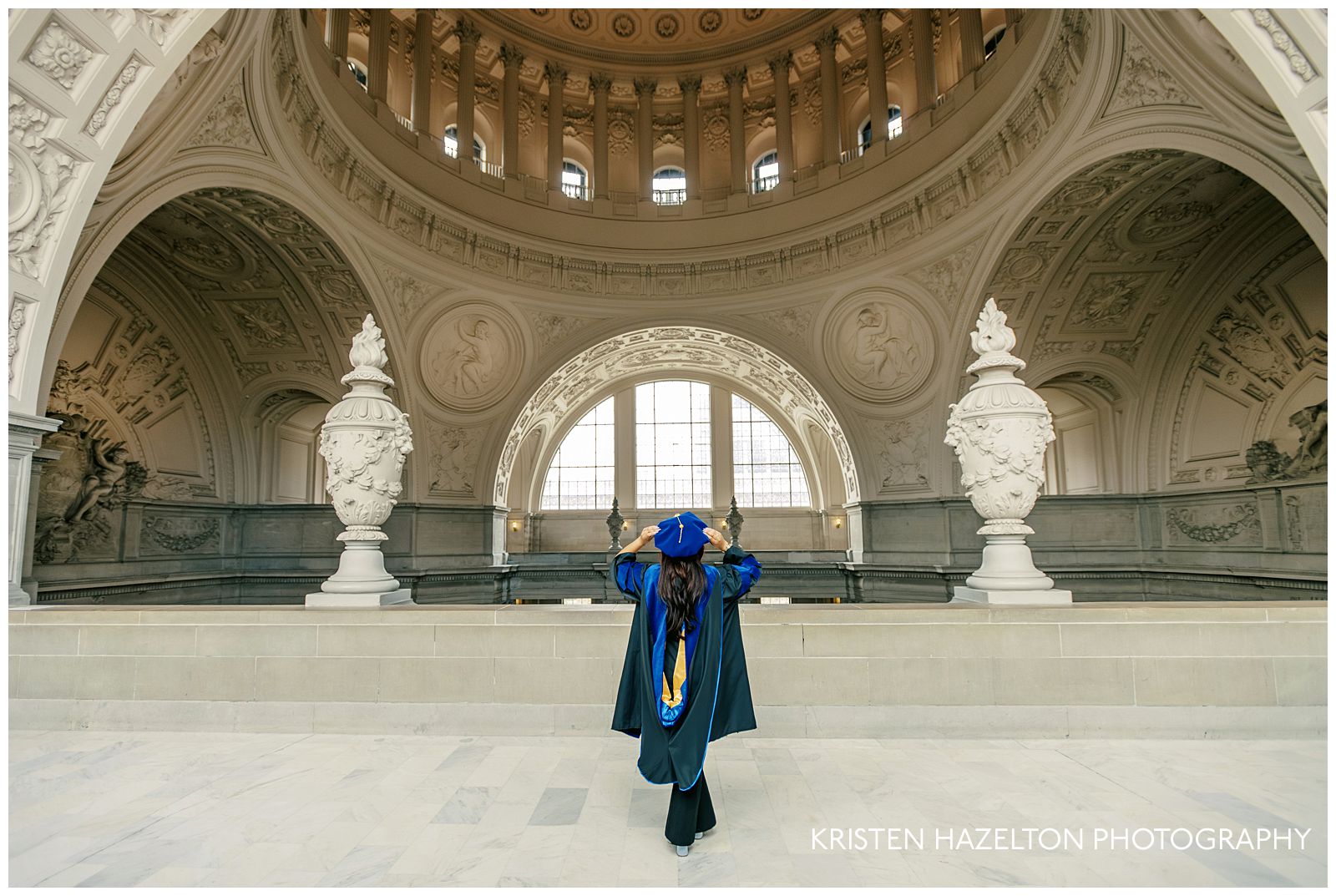 PhD grad student wearing blue regalia taking grad portraits at her San Francisco City Hall photoshoot